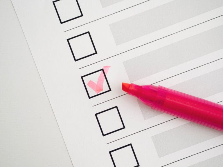 Synthesis Peptides - A checklist with empty boxes, one checked with a pink mark. A pink highlighter pen rests on the paper near the marked box, suggesting tasks related to research peptides or documentation about peptides.